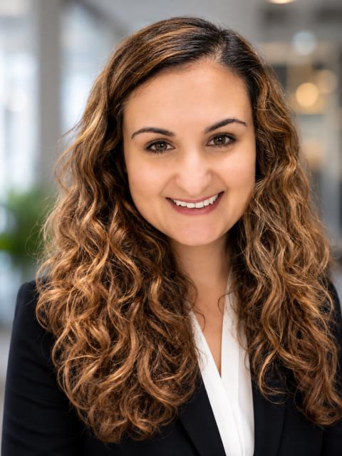 Portait of woman with long curly hair wearing a white shirt and black blazer