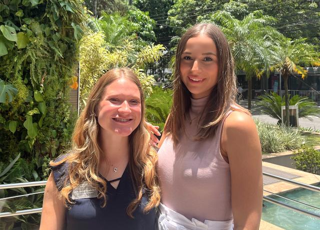 Two young women in Brazil standing outside on a lush sunny day