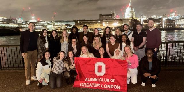 Large group of students posing outside with a flag.