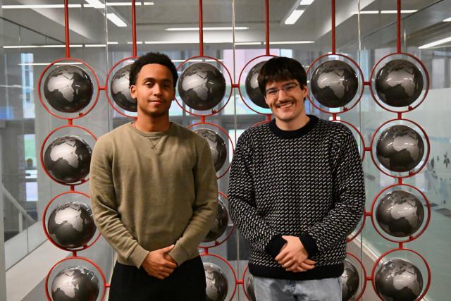 Two students pose in front of globes