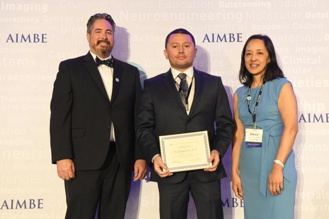 Three people at awards ceremony.