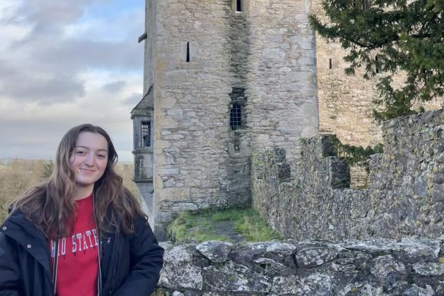 Young woman poses in front of Irish castle