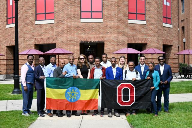 Group of Ethiopian leaders and Ohio State administrators hold the Ethiopian flag and the Ohio State flag in front of the Fisher College of Business