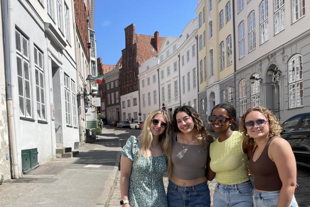 Four young women pose on a European street