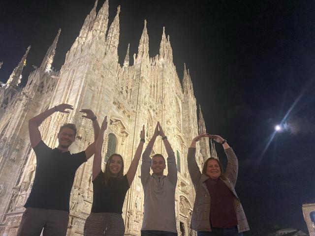 Four people do O-H-I-O in front of Italian cathedral