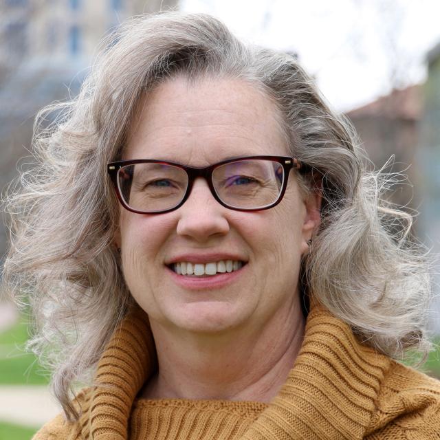 Female wearing brown glasses and mustard sweater.