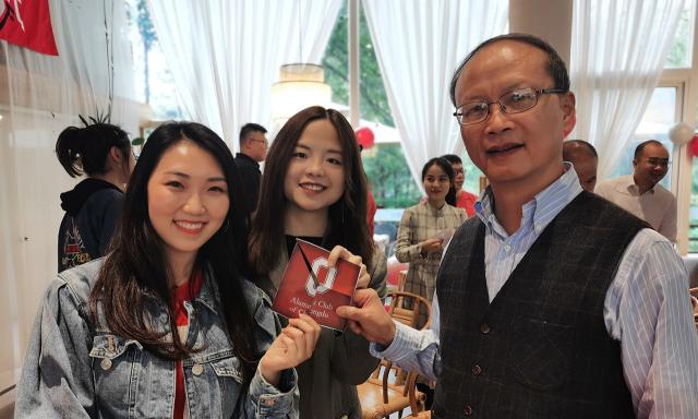 Students holding up a Alumni Club of Chengdu card with a professor