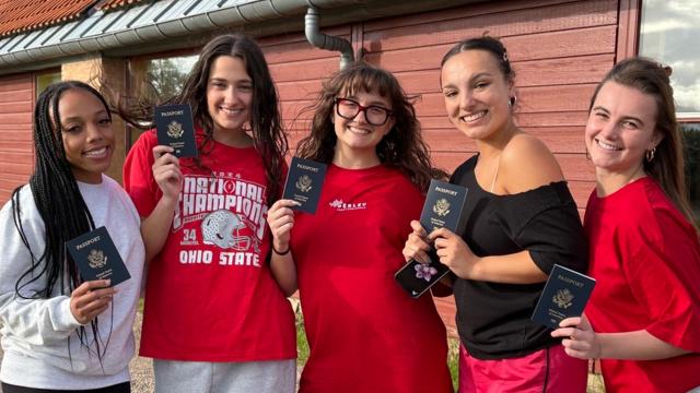 students holding up passports