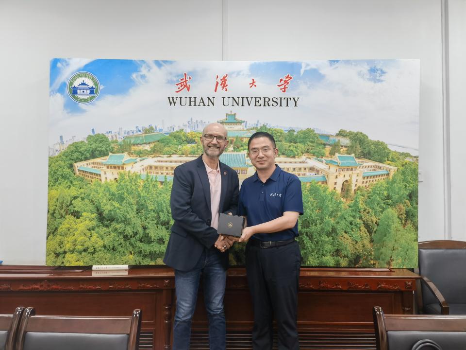 Two men pose while shaking hands