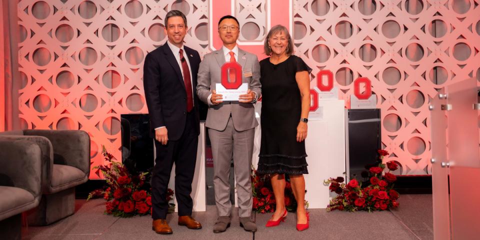 Two men and a woman on stage at awards ceremony