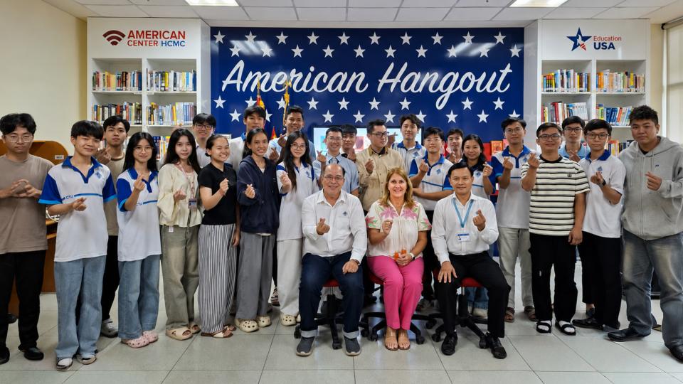 Large group of people with American Hangout banner on wall.