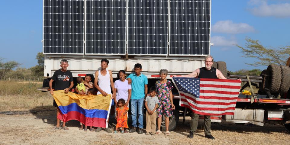 People holding Colombia and U.S. flags by solar panel.