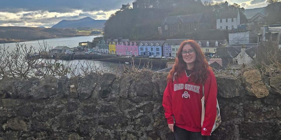 Student on a stone bridge overlooking waterfront village
