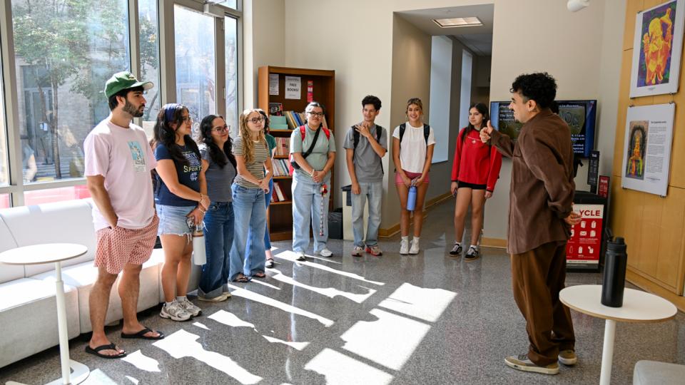 Students casually dressed standing in an exhibition space.