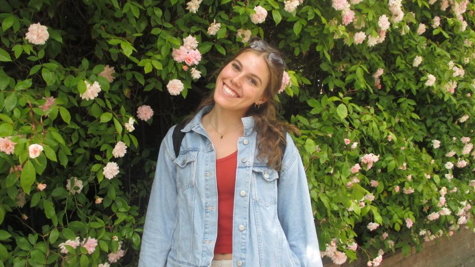 Student in front of shrub and flower wall