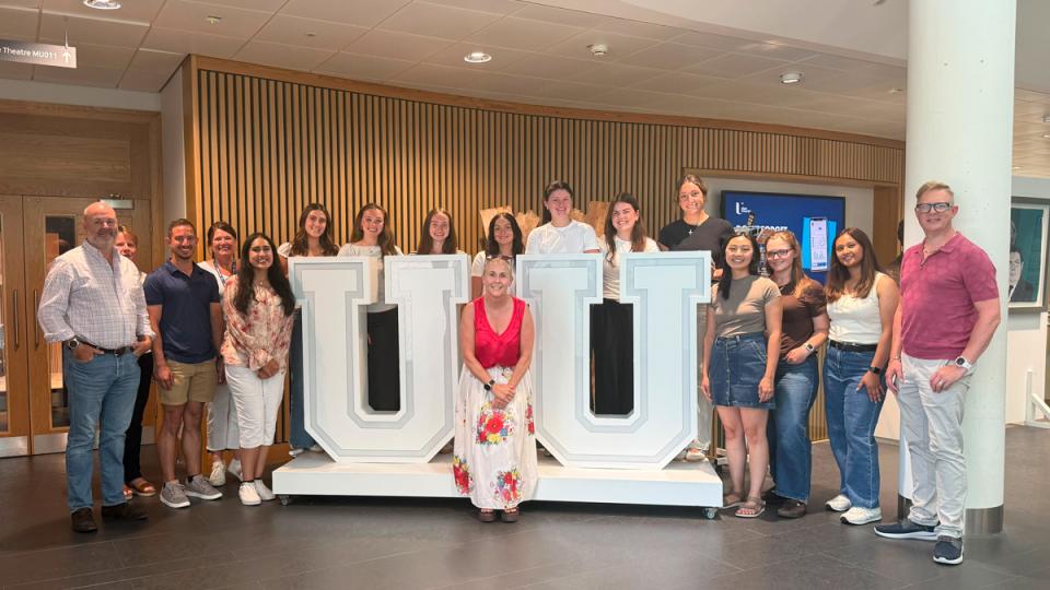 Students and faculty pose by UU sign.