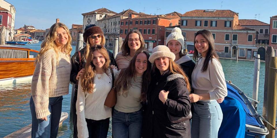 Students posing as a group with water and city buildings in the background