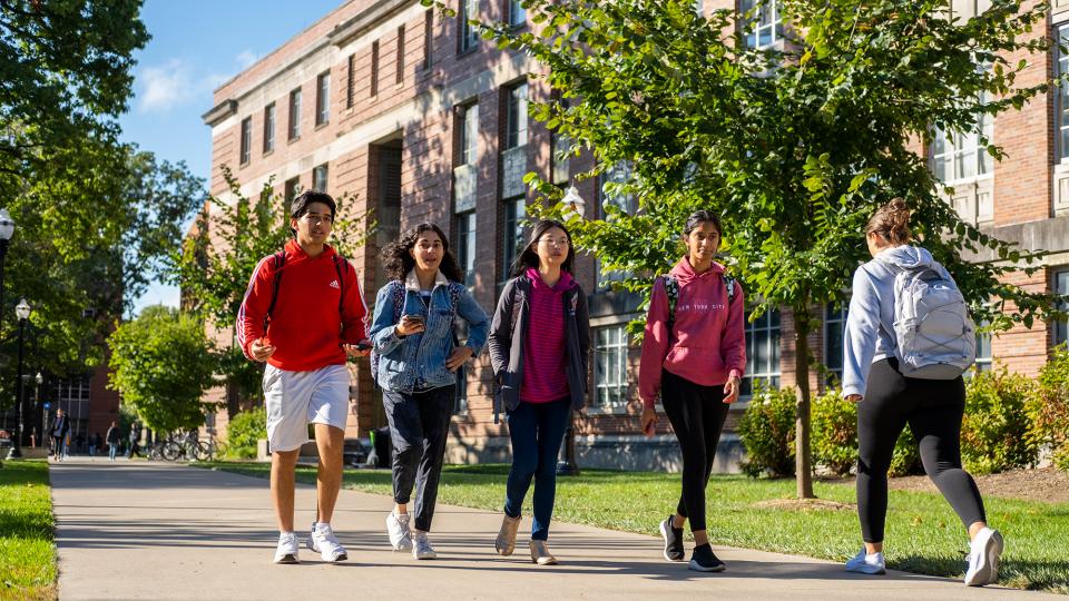 Group of Students walking across campus on a bright day