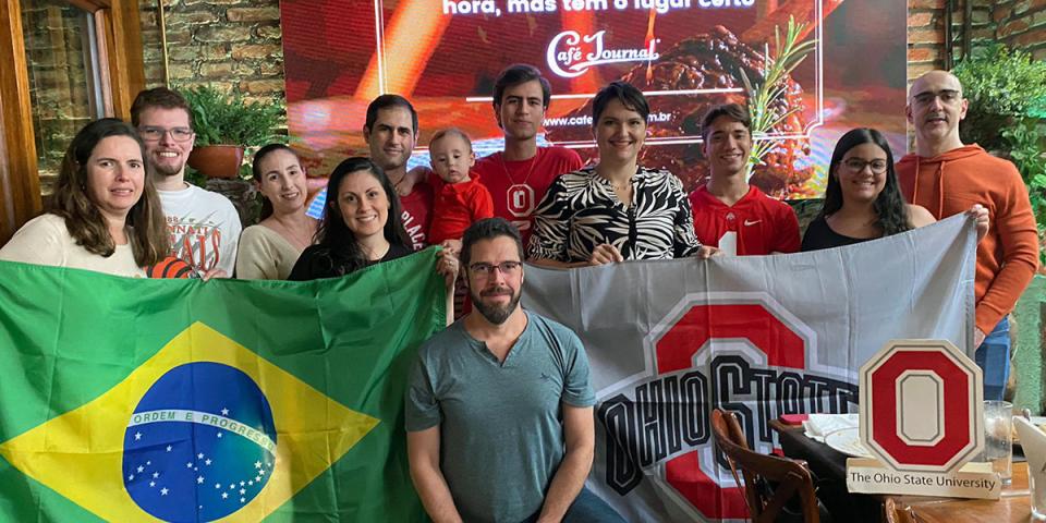 A group of people standing with the Brazil and Ohio State flags at the Brazil Send Off Event.