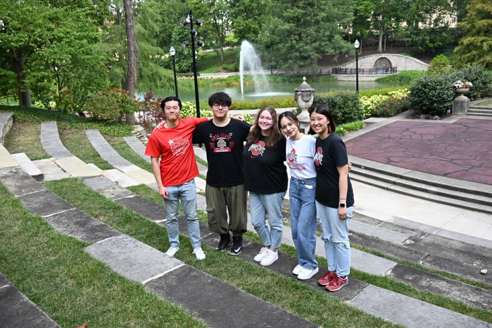 Students in Ohio State global engagement tee shirts standing by mirror lake