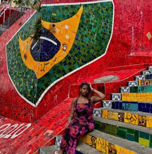Woman sitting on steps in front of Brazil flag mosaic