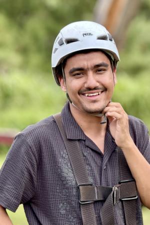 Man smiling wearing a helmet in outdoor setting