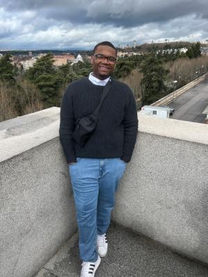 Male standing by wall with city in background
