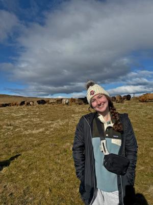 Person standing in a field with ruminants in the background