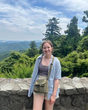 student standing in front of a lush countryside