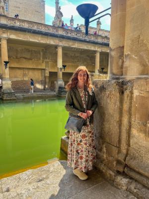 Woman stands by Roman bath.