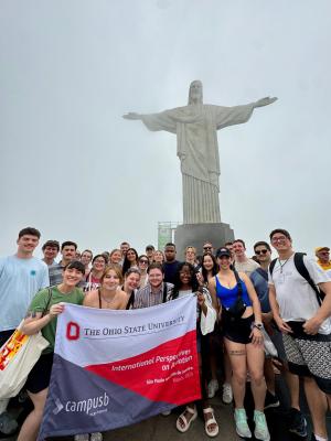 Group holding flag in front of Christ the Redeemer statue