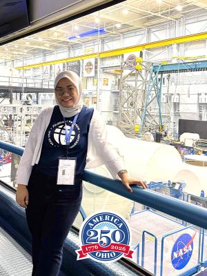 Woman wearing a head scarf standing in aerospace facility.