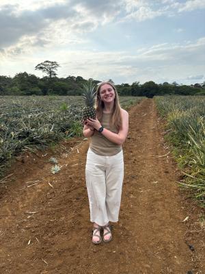 Student holding a pineapple on a farm