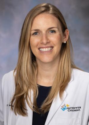 Blonde woman smiling wearing a white lab coat.