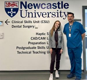 Man and woman in front of sign for Newcastle University