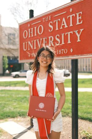 Woman holding diploma in front of Ohio State sign