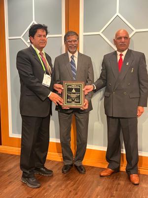 Three men, one holding a plaque